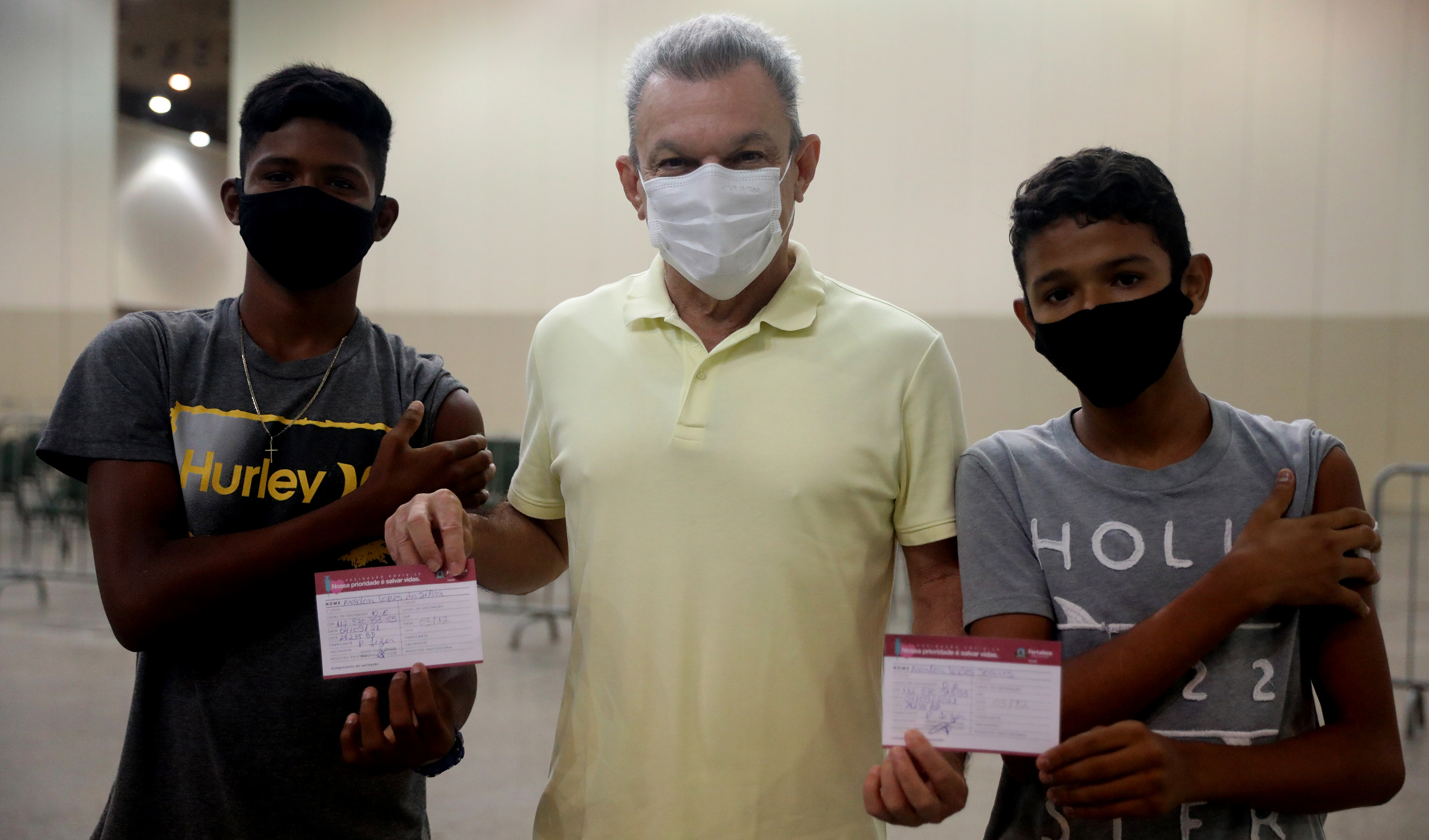 sarto e dois adolescentes segurando seus cartões de vacinção posam para a foto